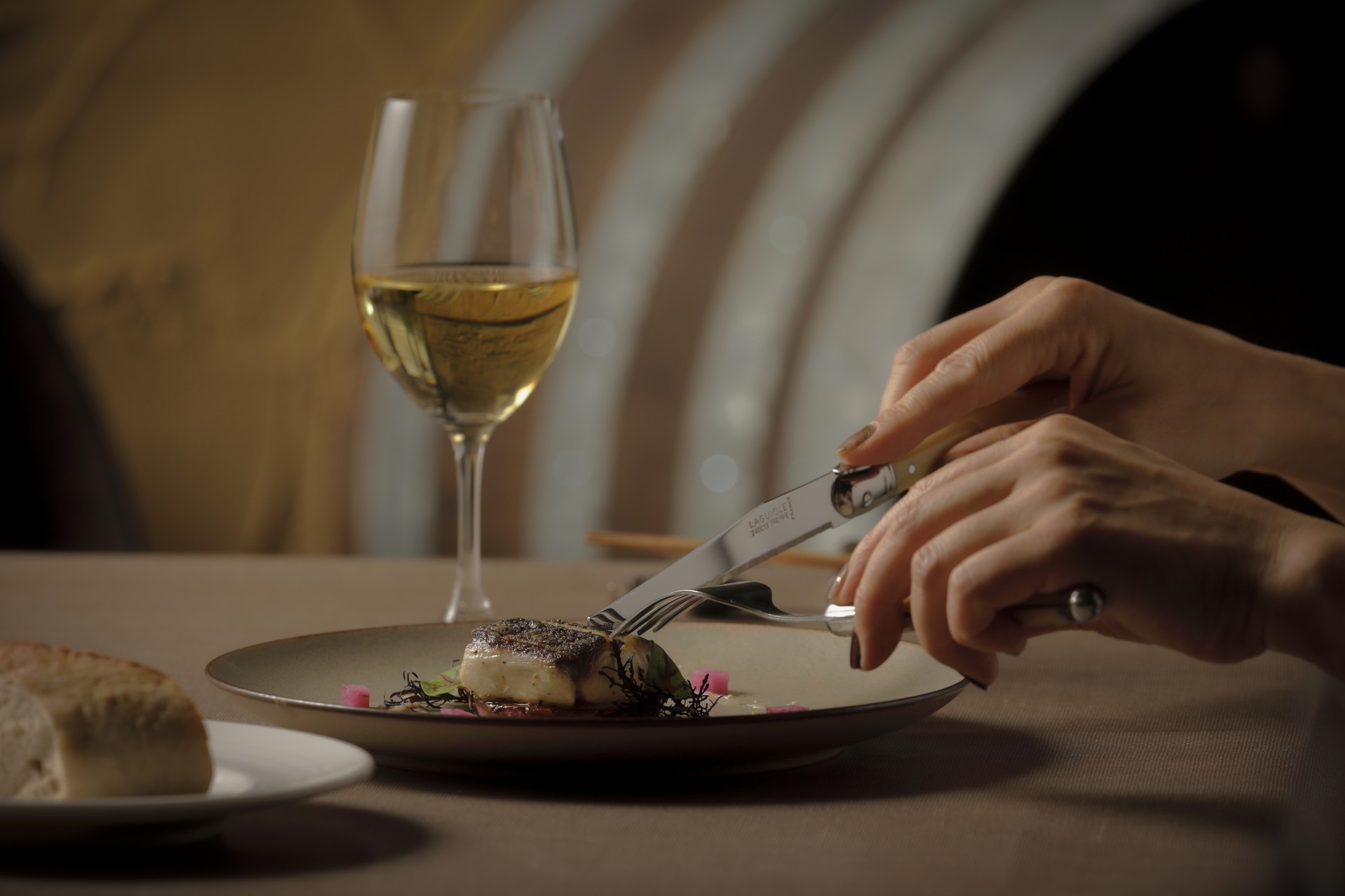 a person eating food on a plate with a glass of wine