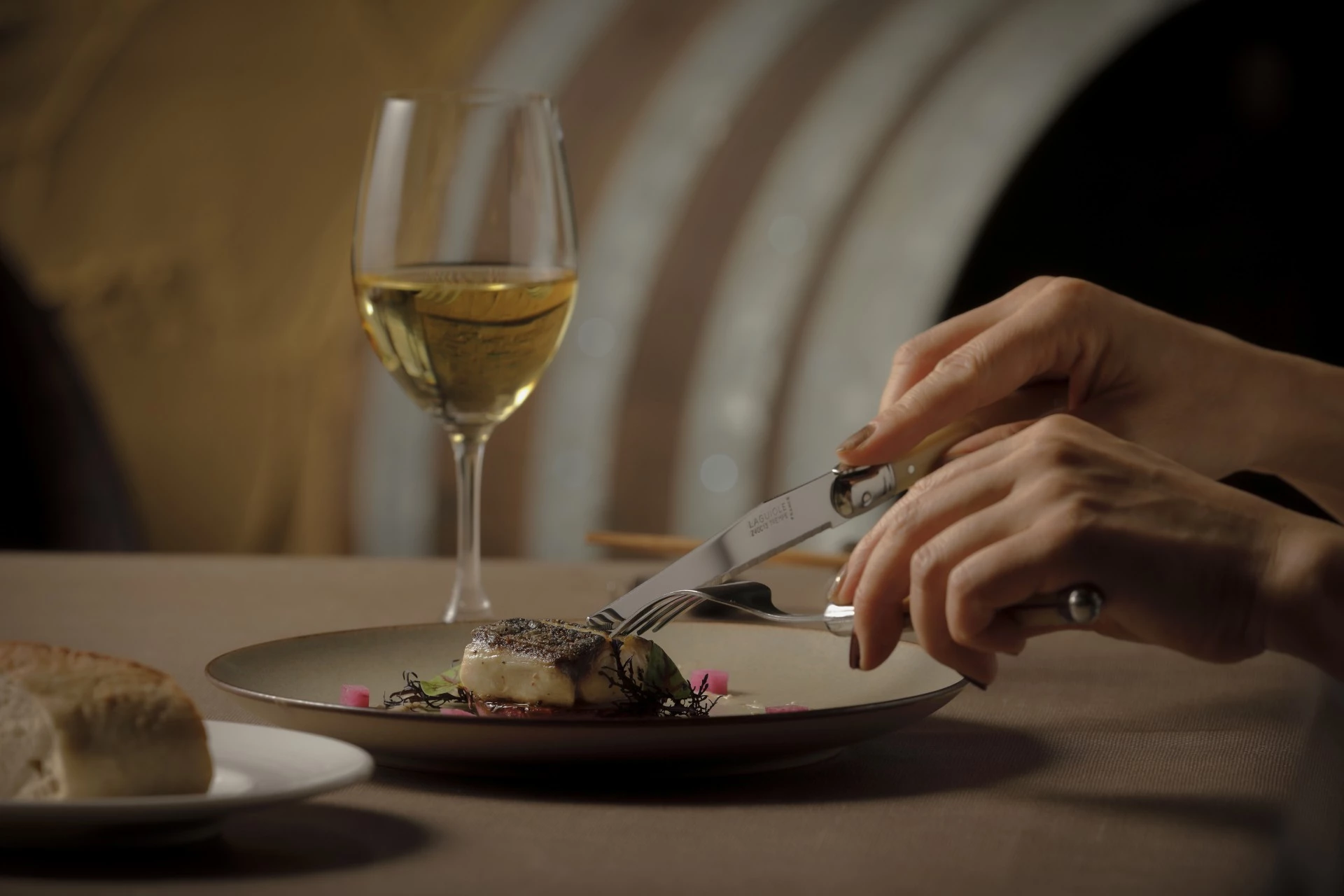 a person eating food on a plate with a glass of wine
