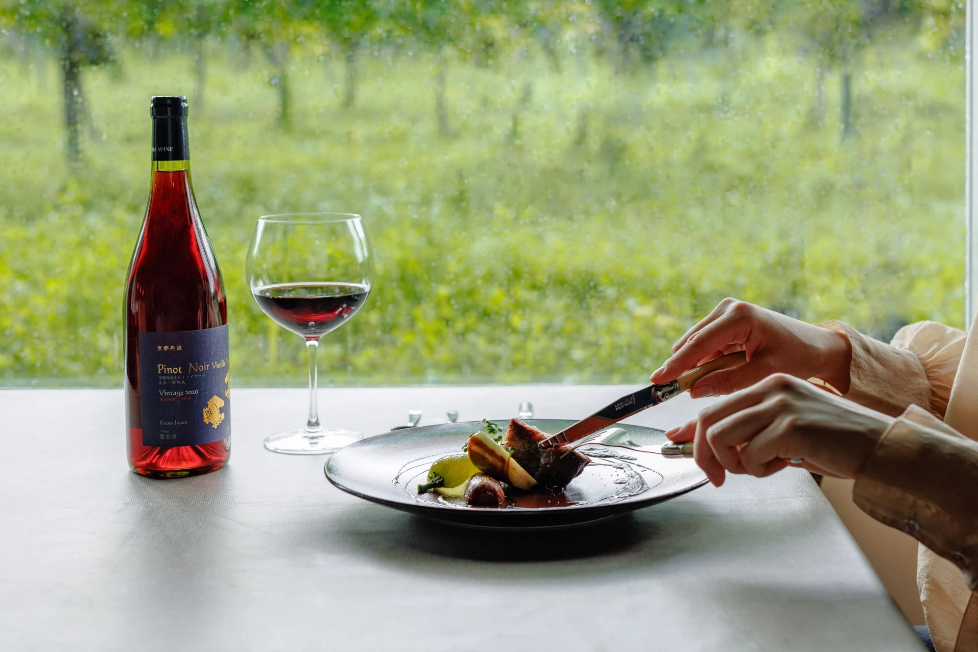 a person eating food on a plate with a bottle of wine
