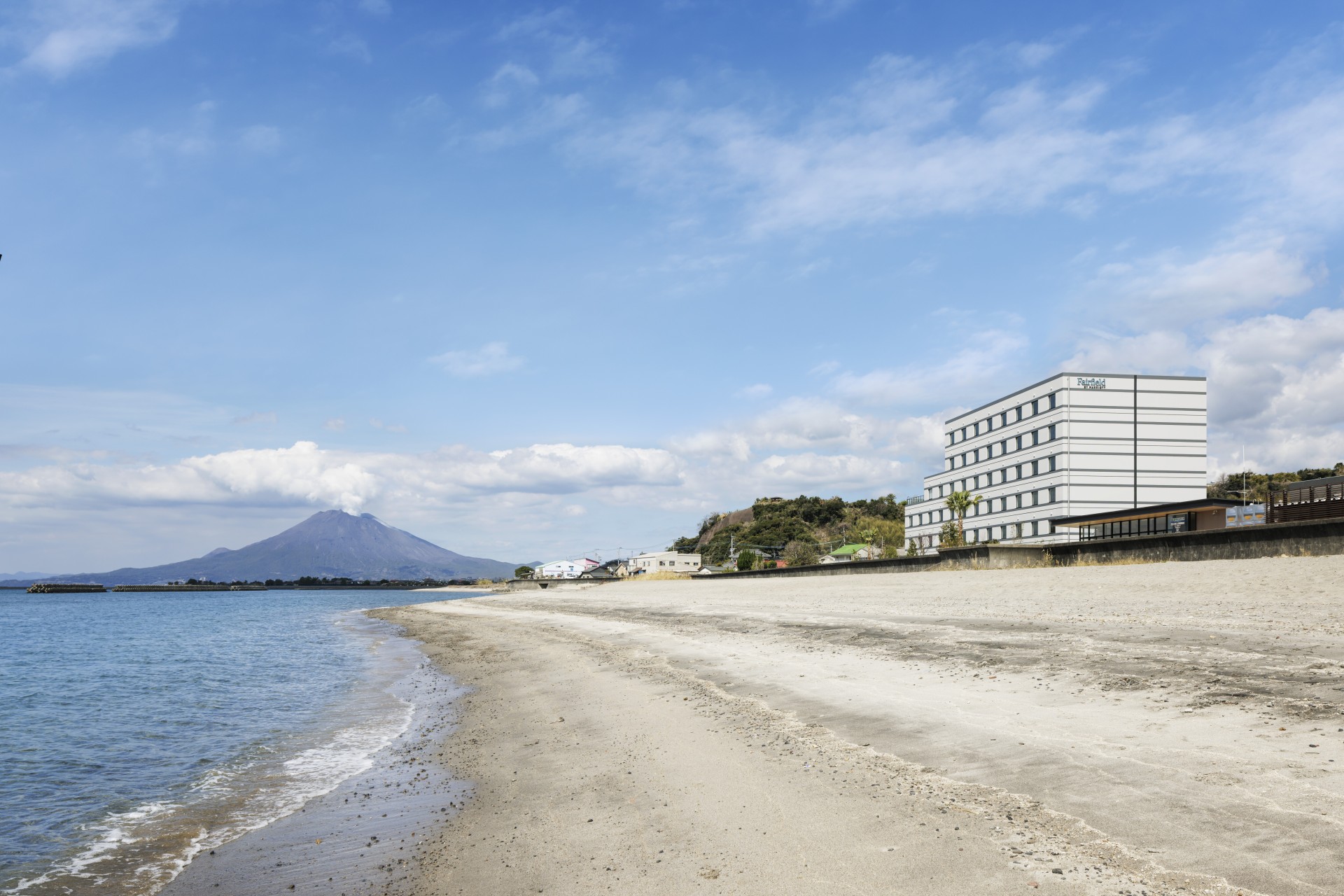 a beach with a building and a mountain in the background