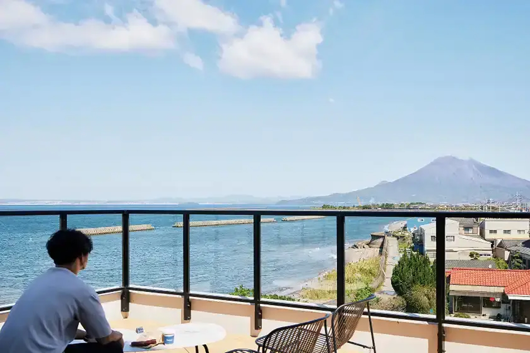 a man sitting on a balcony overlooking water and mountains