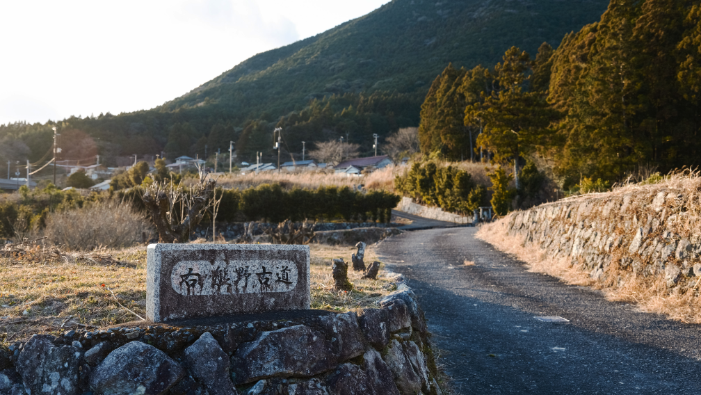 a stone sign on a rock wall with trees in the background
