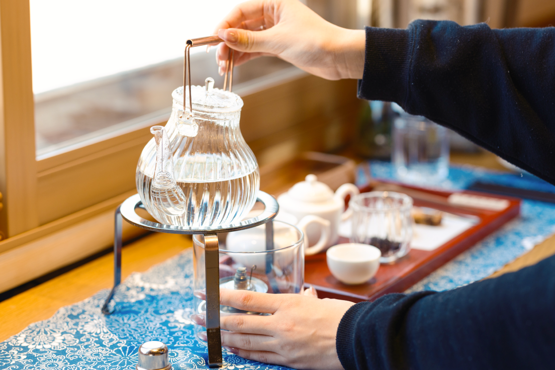 a person pouring water into a glass container