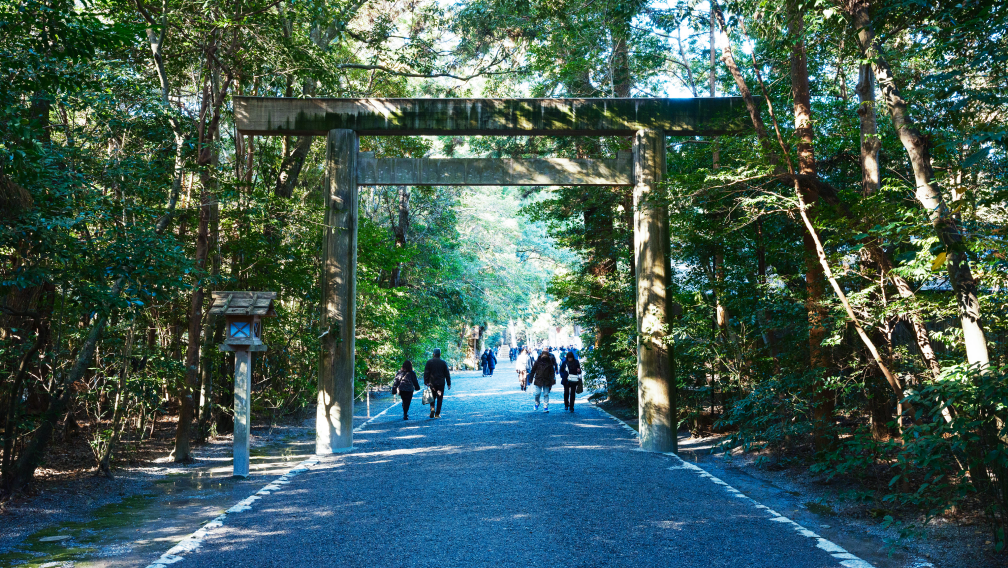 a group of people walking on a path with a large wooden arch