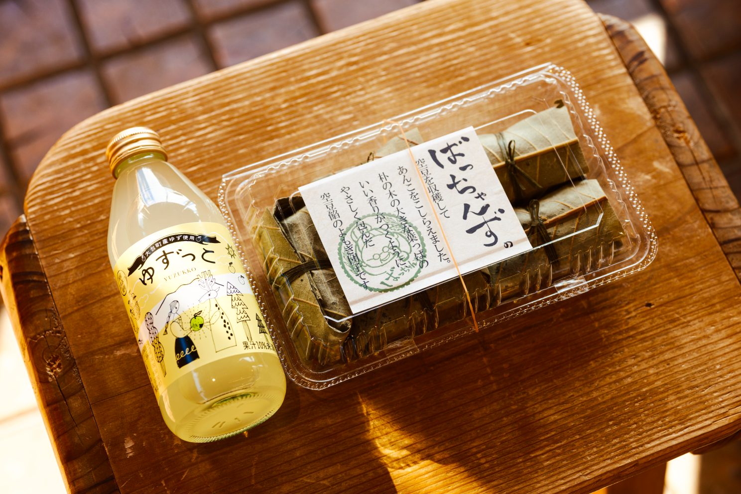 a plastic container with food wrapped in green wrappers next to a bottle of liquid