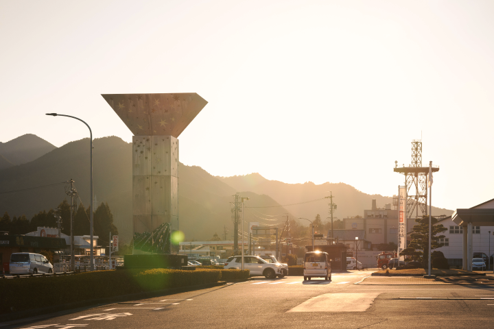 a street with a tower and cars in the background