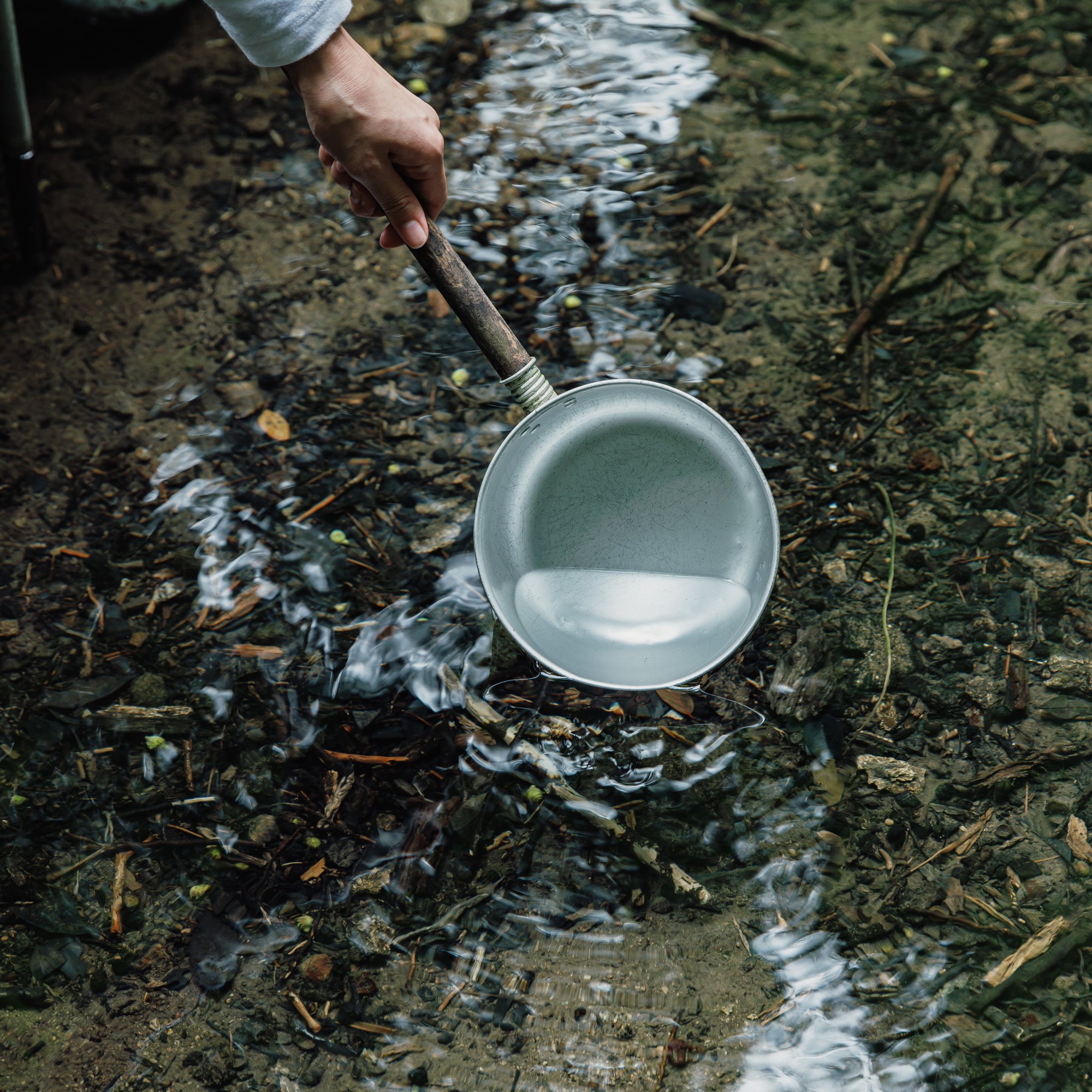 a hand holding a pan over water