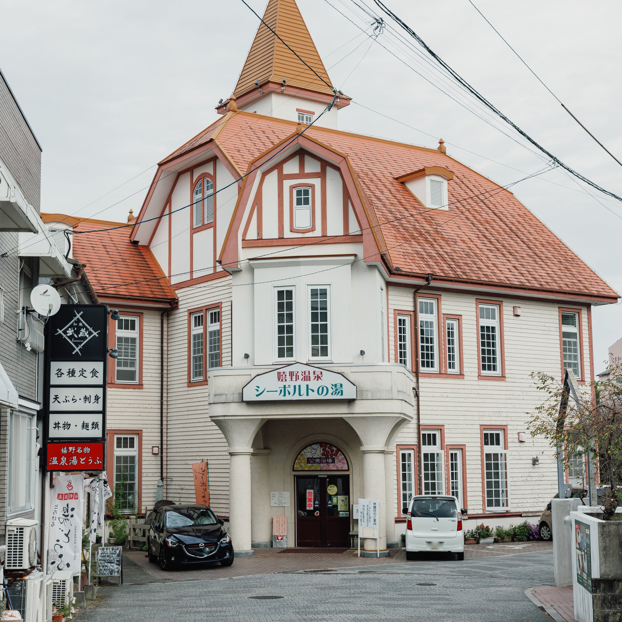 Singapore Philatelic Museum with a steeple and cars parked in front of it