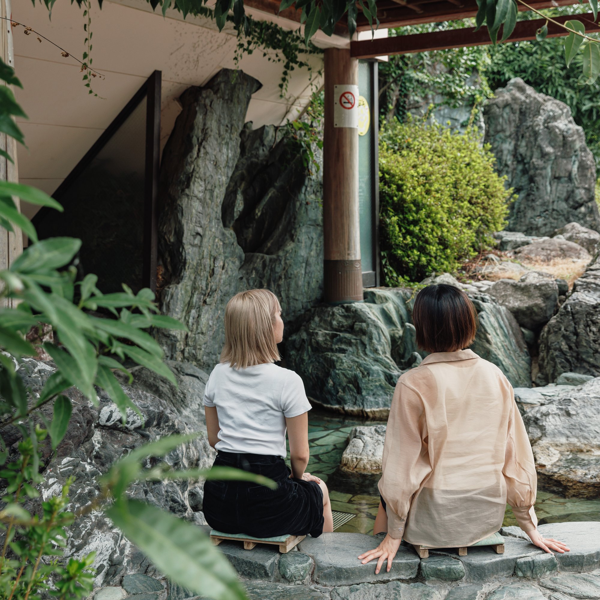 two women sitting on a rock ledge