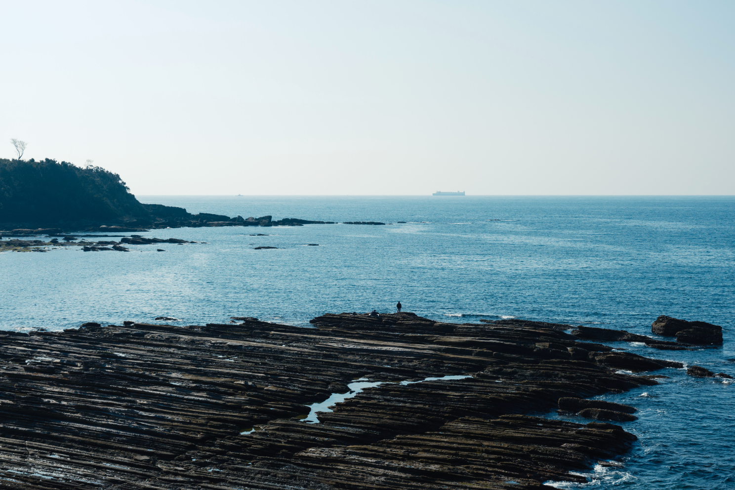 a rocky beach with a boat in the distance