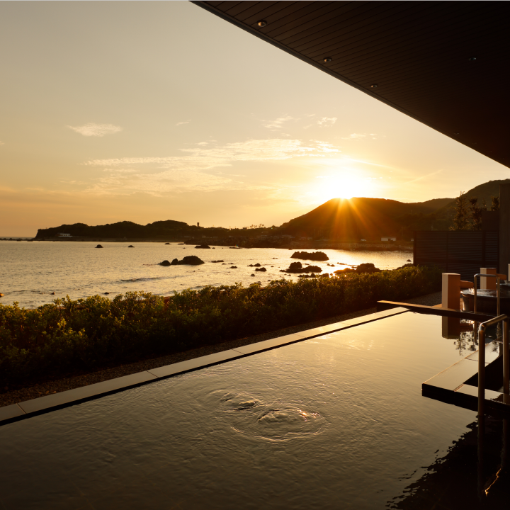 a pool with a view of the ocean and mountains in the background