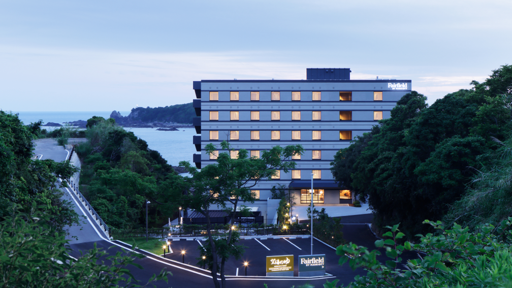 a building with many windows and a parking lot next to the water