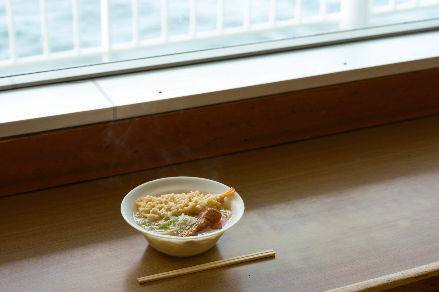 a bowl of soup with chopsticks and a window