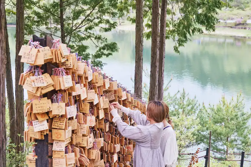 a woman touching a wall of small wooden plaques