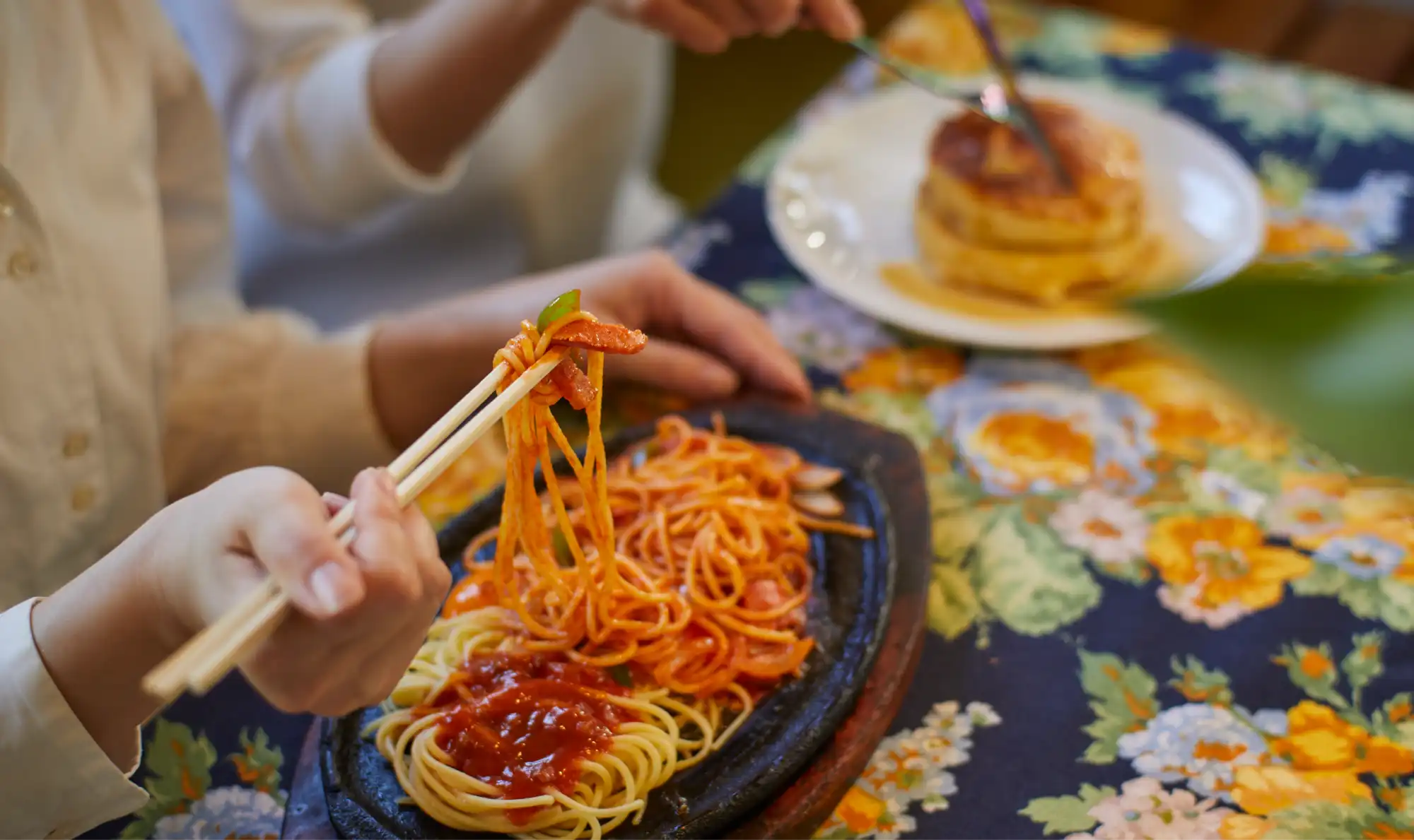a person holding chopsticks over food