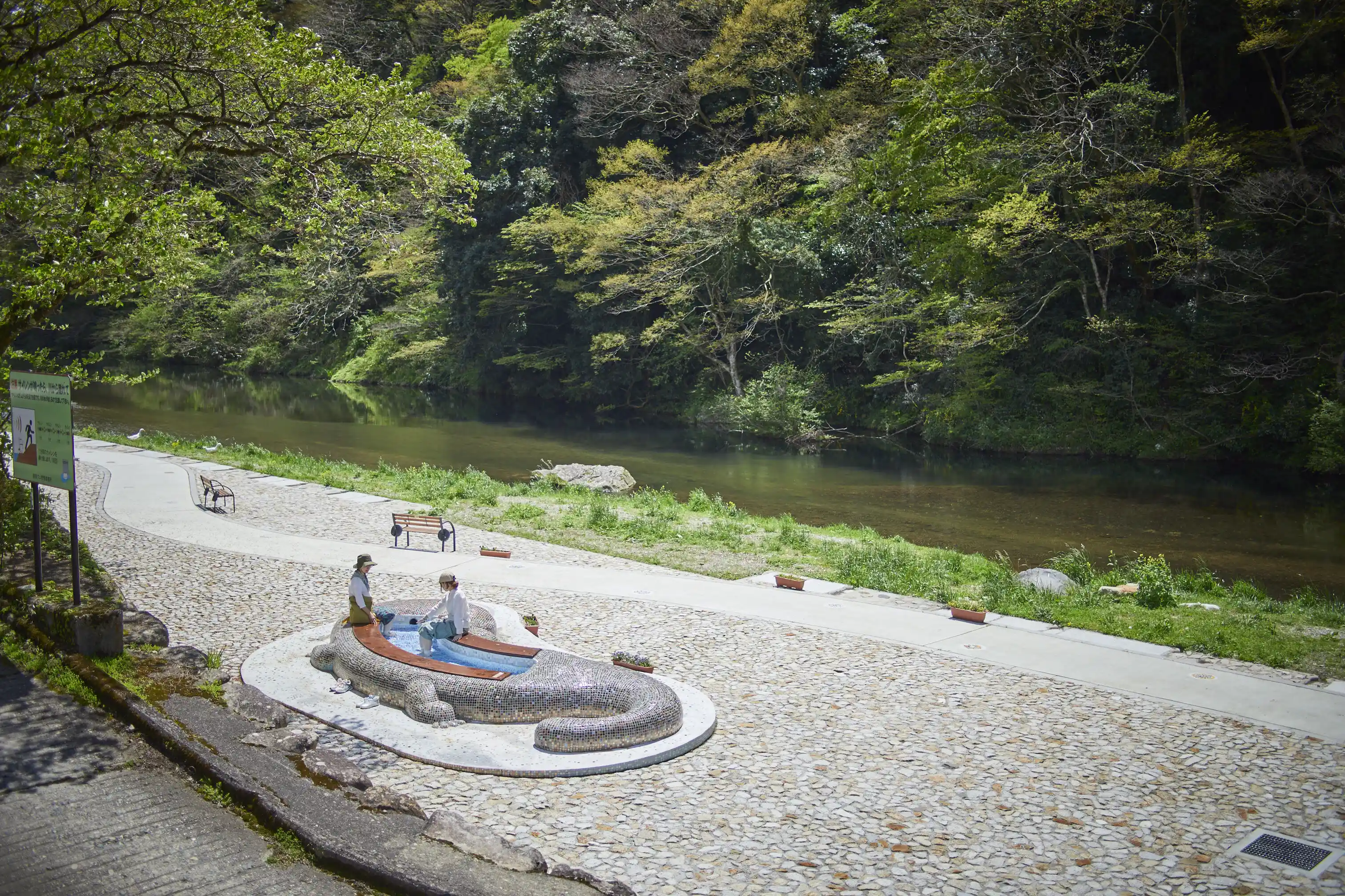 a group of people sitting on a stone bench next to a river