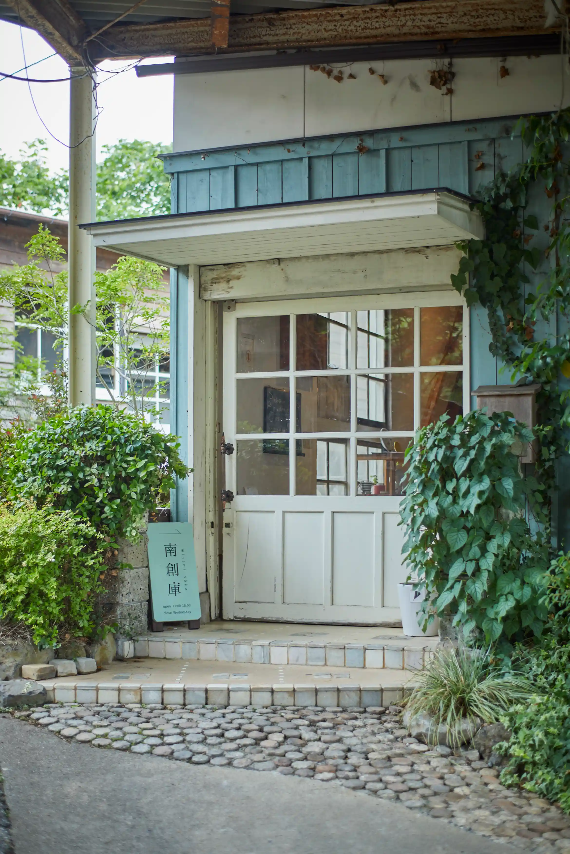a door of a building with plants and a sign
