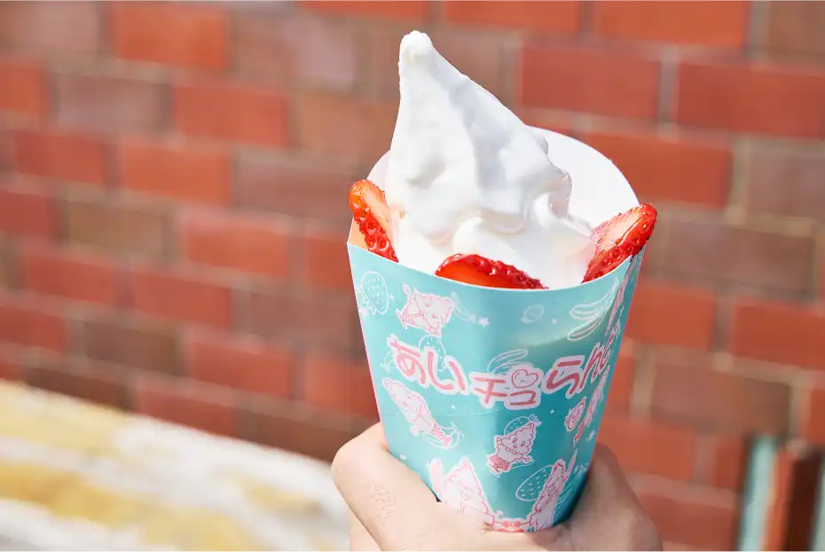 a hand holding a blue cone with strawberries and whipped cream