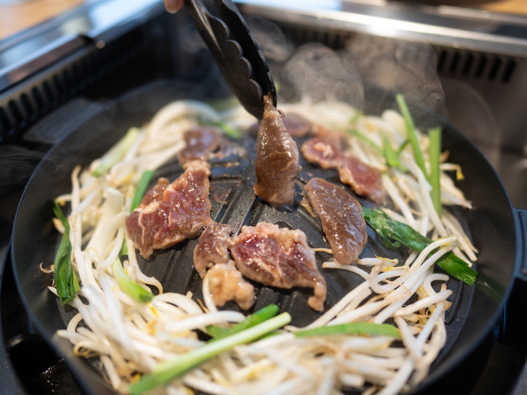 a person cooking meat on a grill