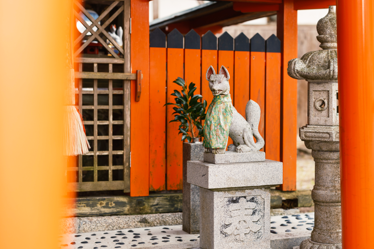 a statue of a fox in front of a red fence