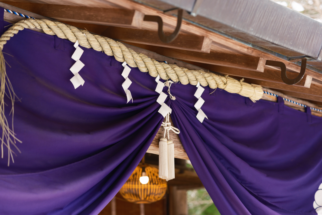 a purple curtain with white tags from a wooden structure