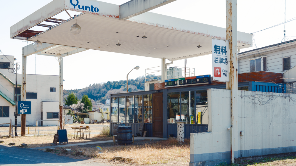 a gas station with a sign and a barrel