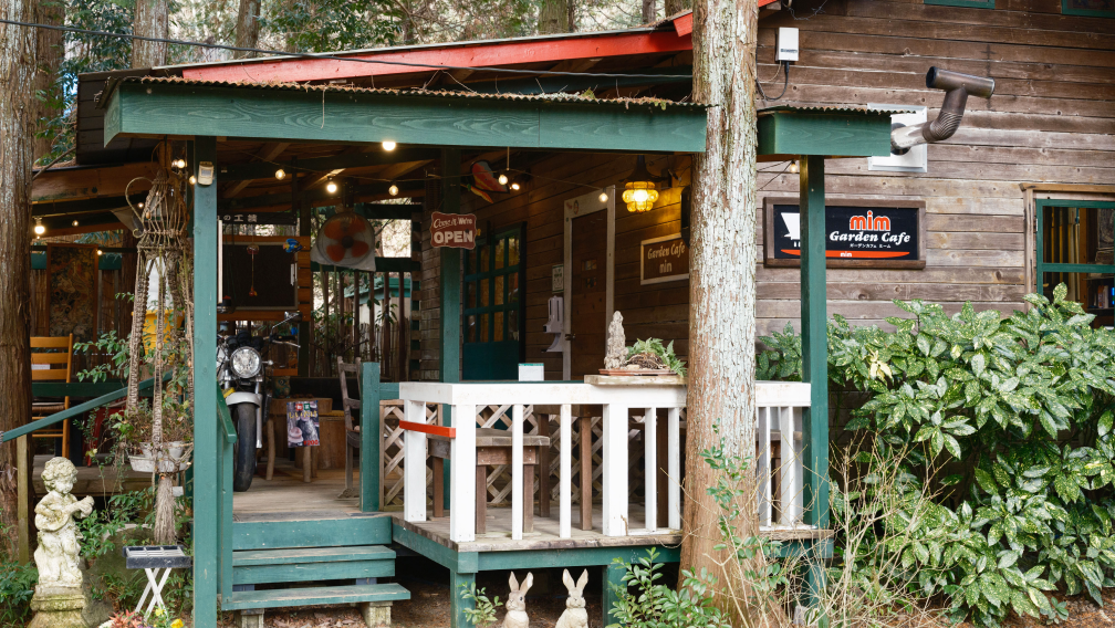 a building with a porch and a motorcycle parked in the woods