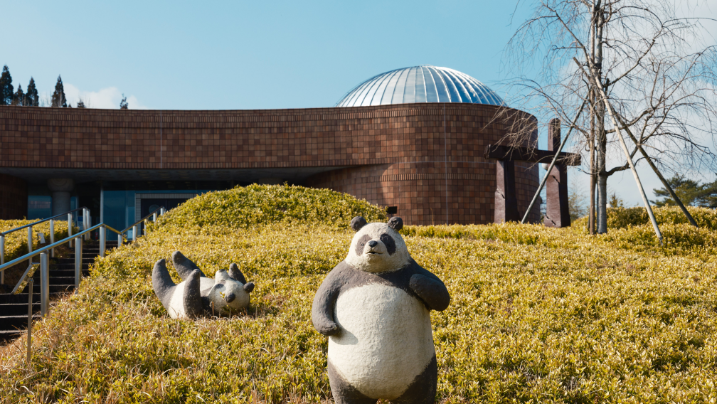 a statue of a panda in a grassy field