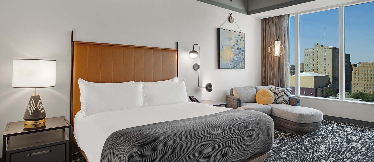 hotel room with spacious bed and grey chaise