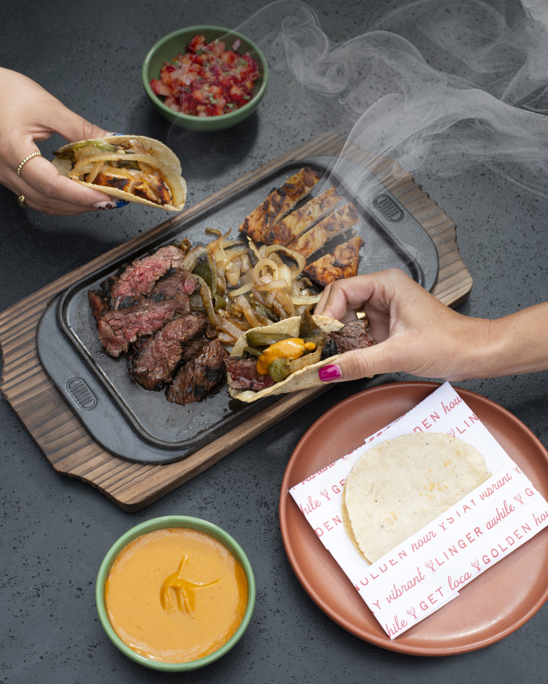 a person holding tacos over a plate of meat