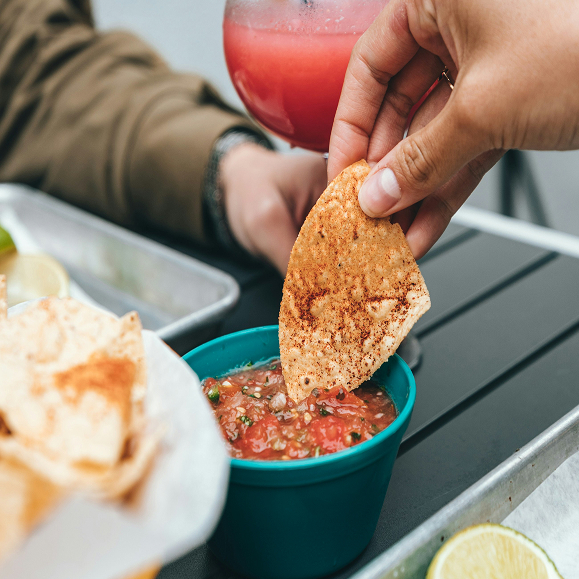 a person dipping a chip into a bowl of salsa