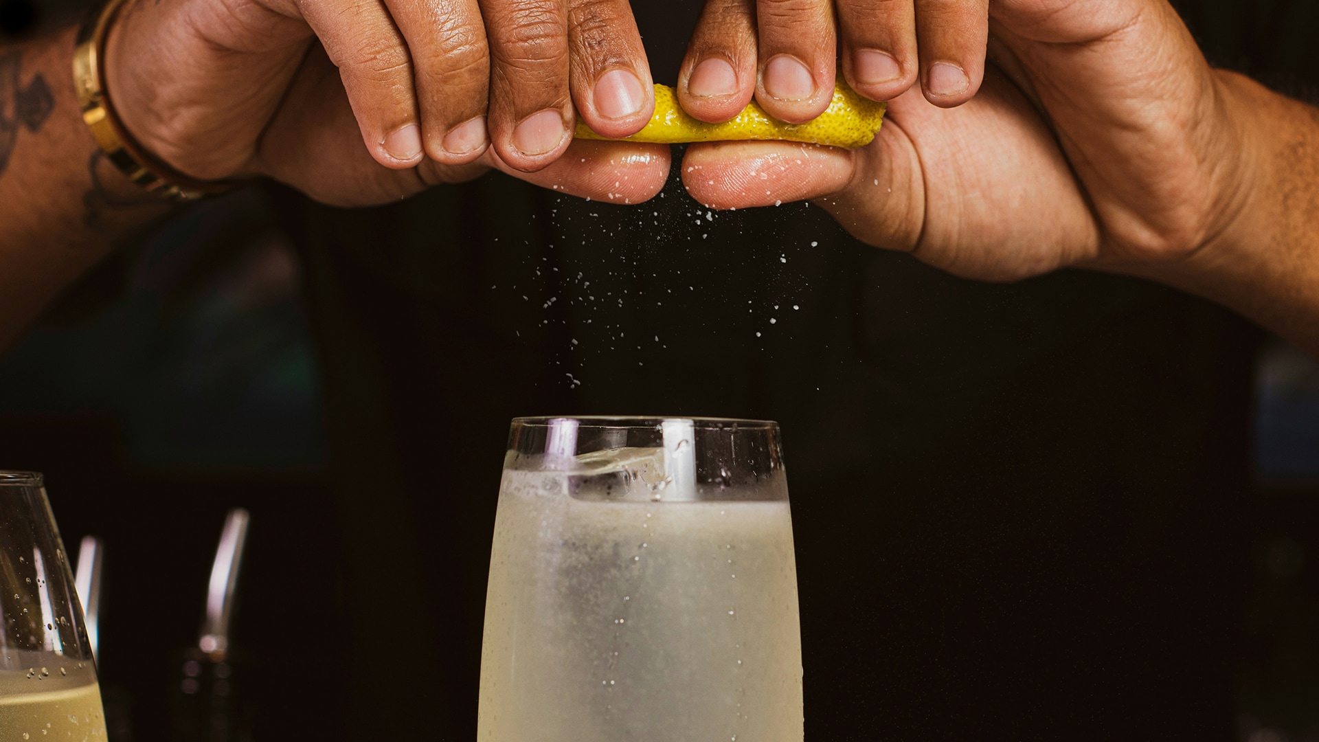 hands squeezing a lemon into a glass of liquid