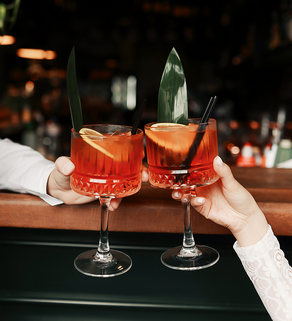 two hands holding glasses with drinks