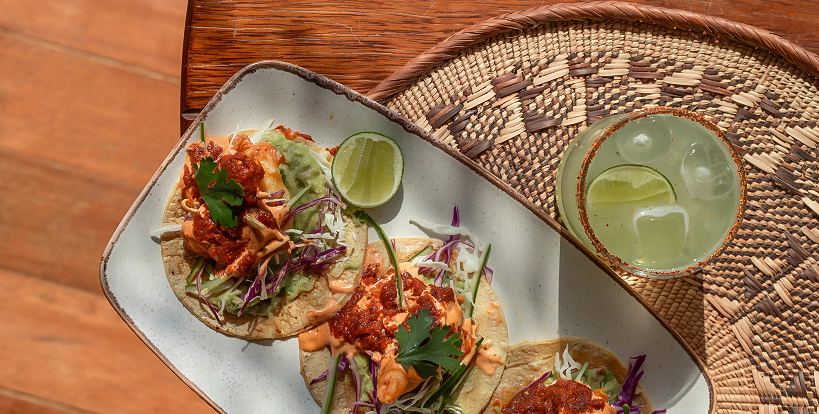 a plate of tacos with sauce and limes