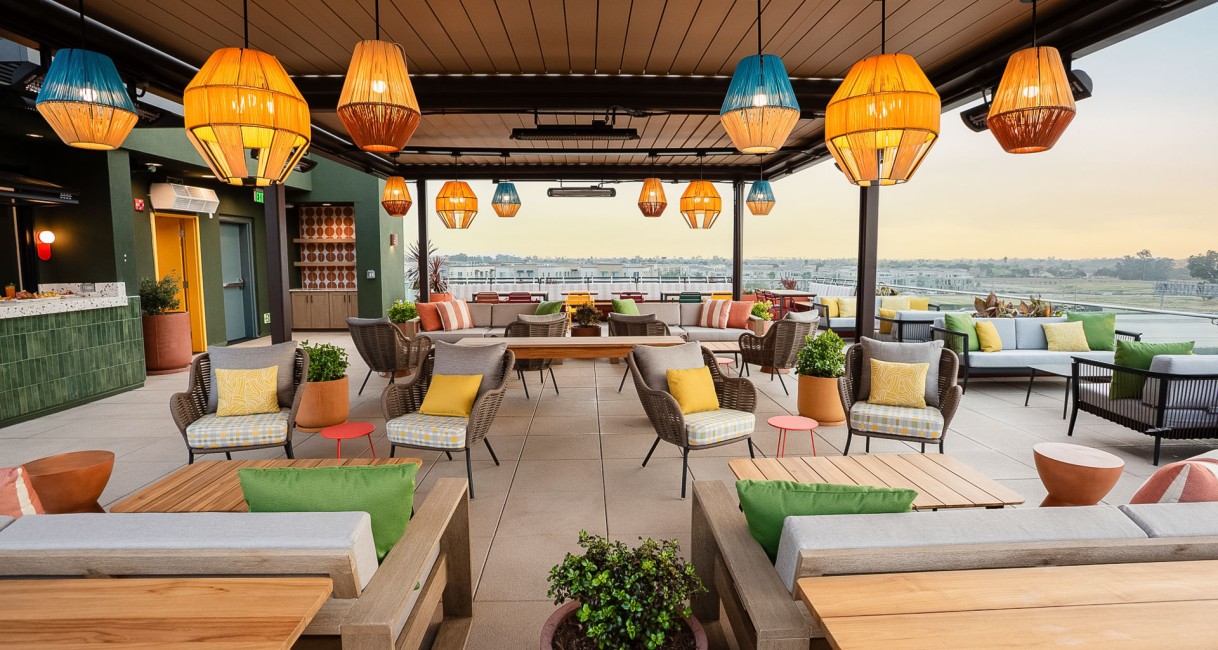a patio with chairs and tables and lamps from the ceiling