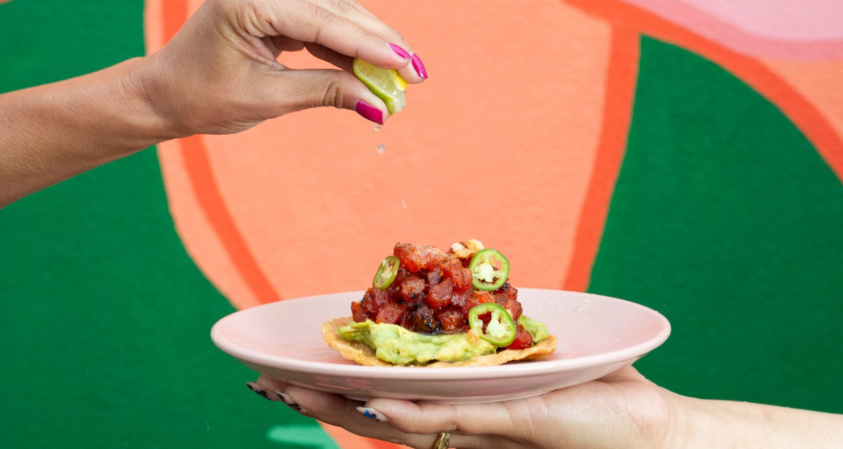 a person pouring a lime juice onto a plate of food