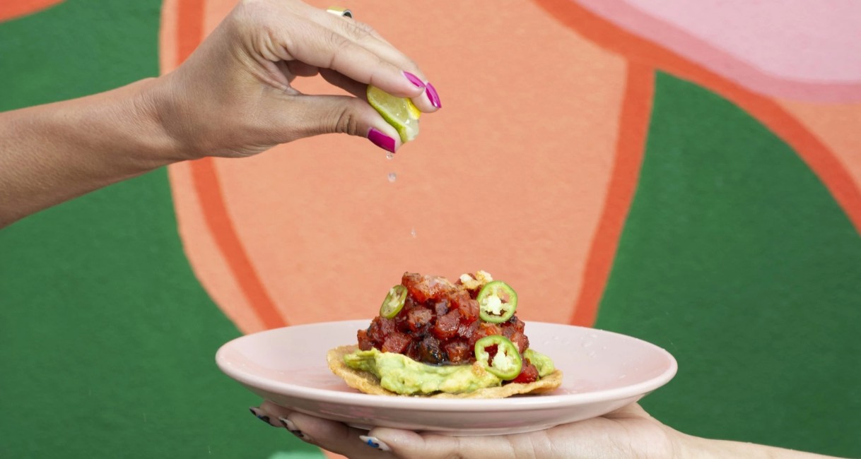 a person squeezing a lemon over a plate of food