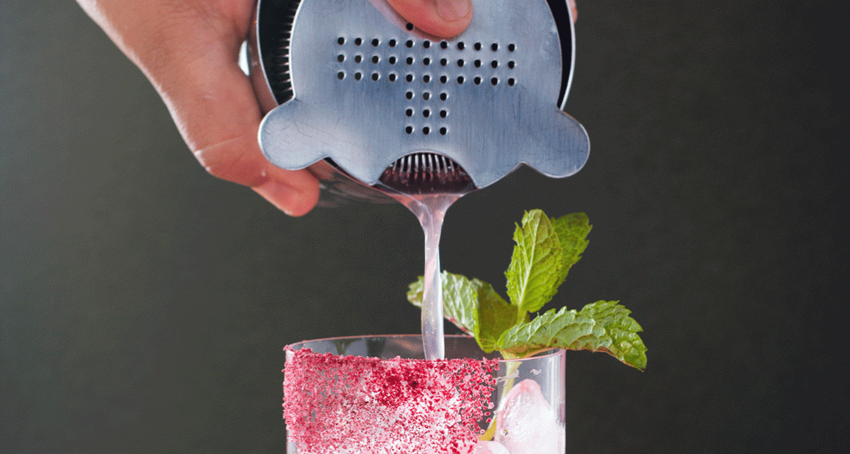a person pouring a drink into a glass