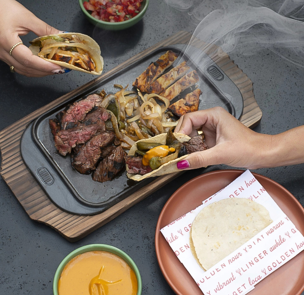 a person holding tacos over a plate of food