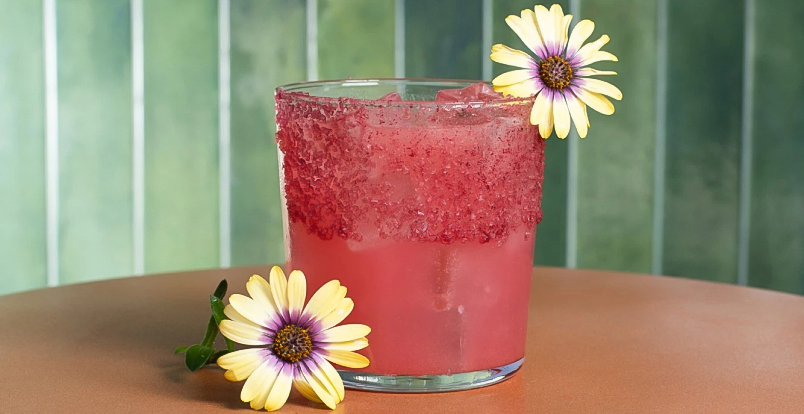 a glass of pink drink with yellow flowers