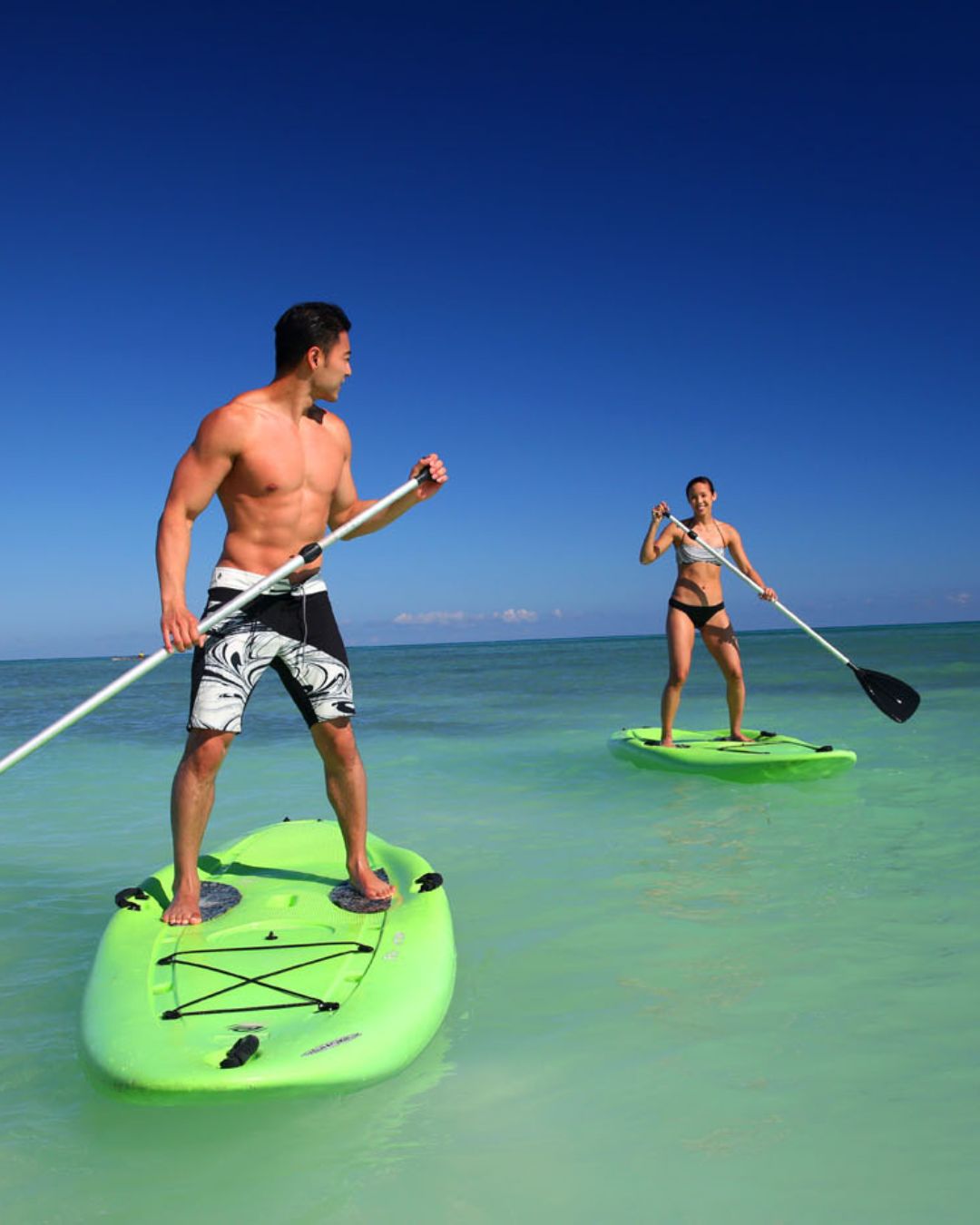 a man and woman on paddle boards in the water