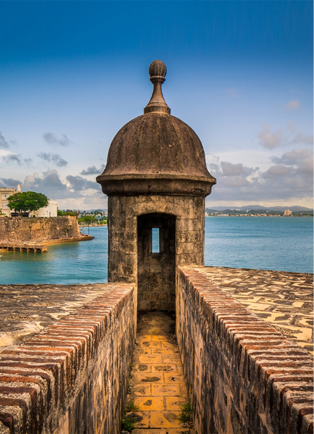a stone tower with a round top and a body of water in the background