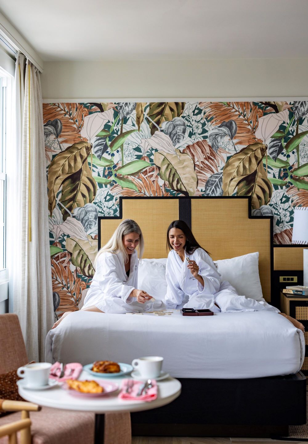 a couple of women in white robes sitting on a bed
