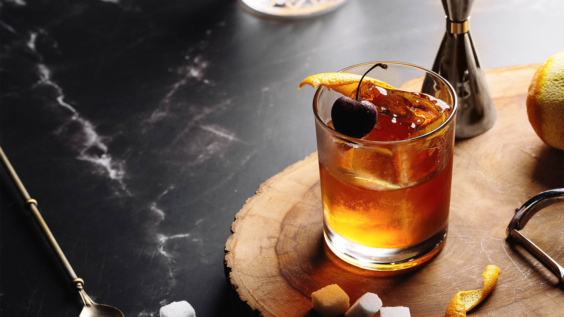 a drink garnished with a cherry and orange peel