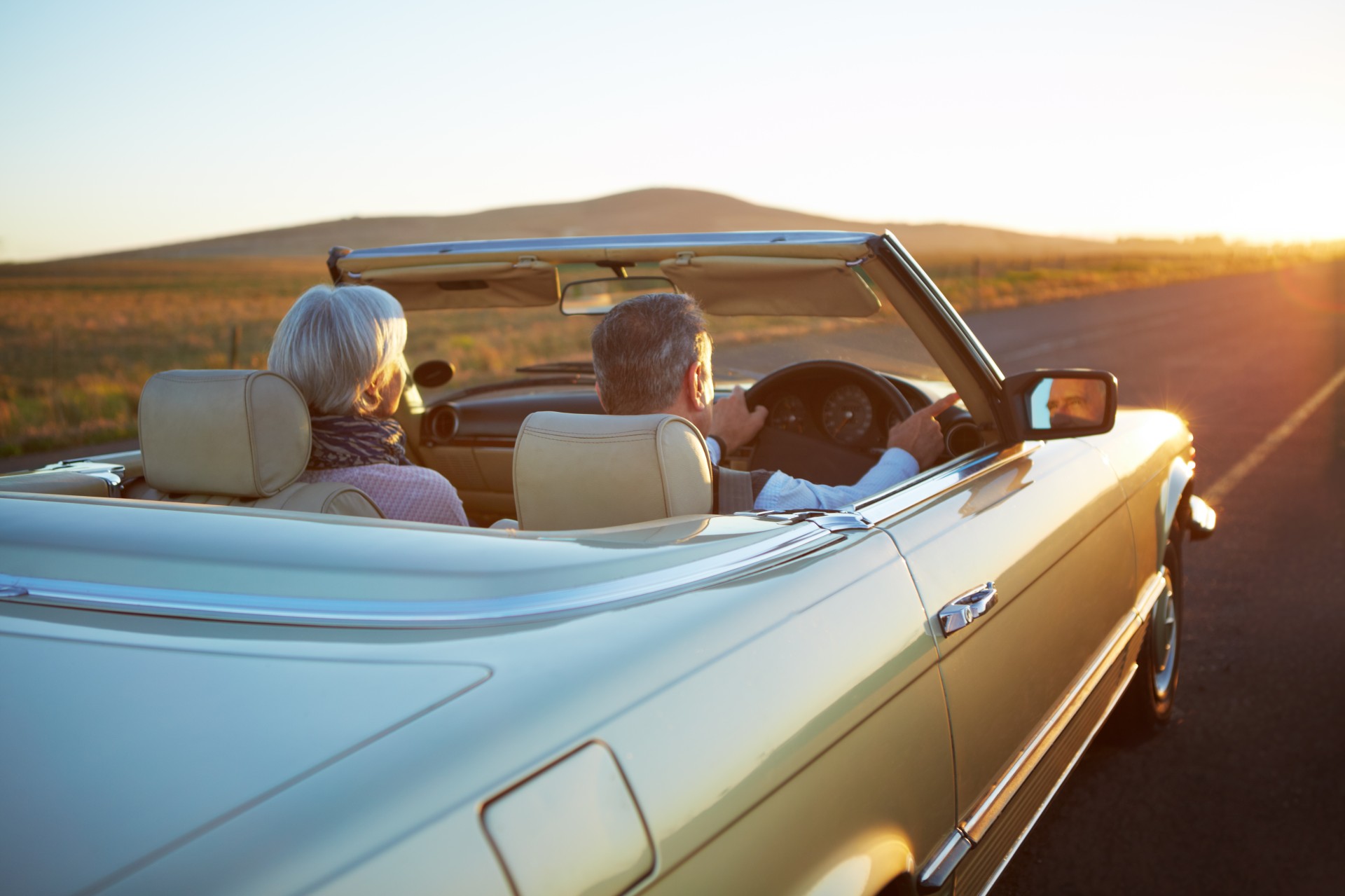 a man and woman driving a convertible car