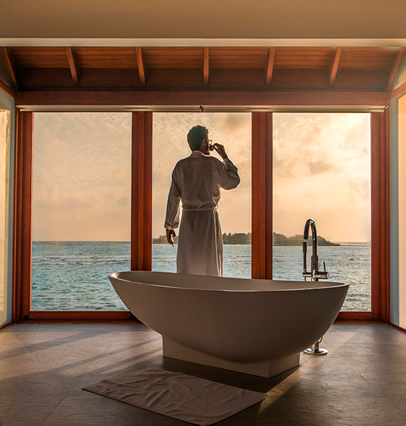 a man in a bathrobe standing in front of a bathtub