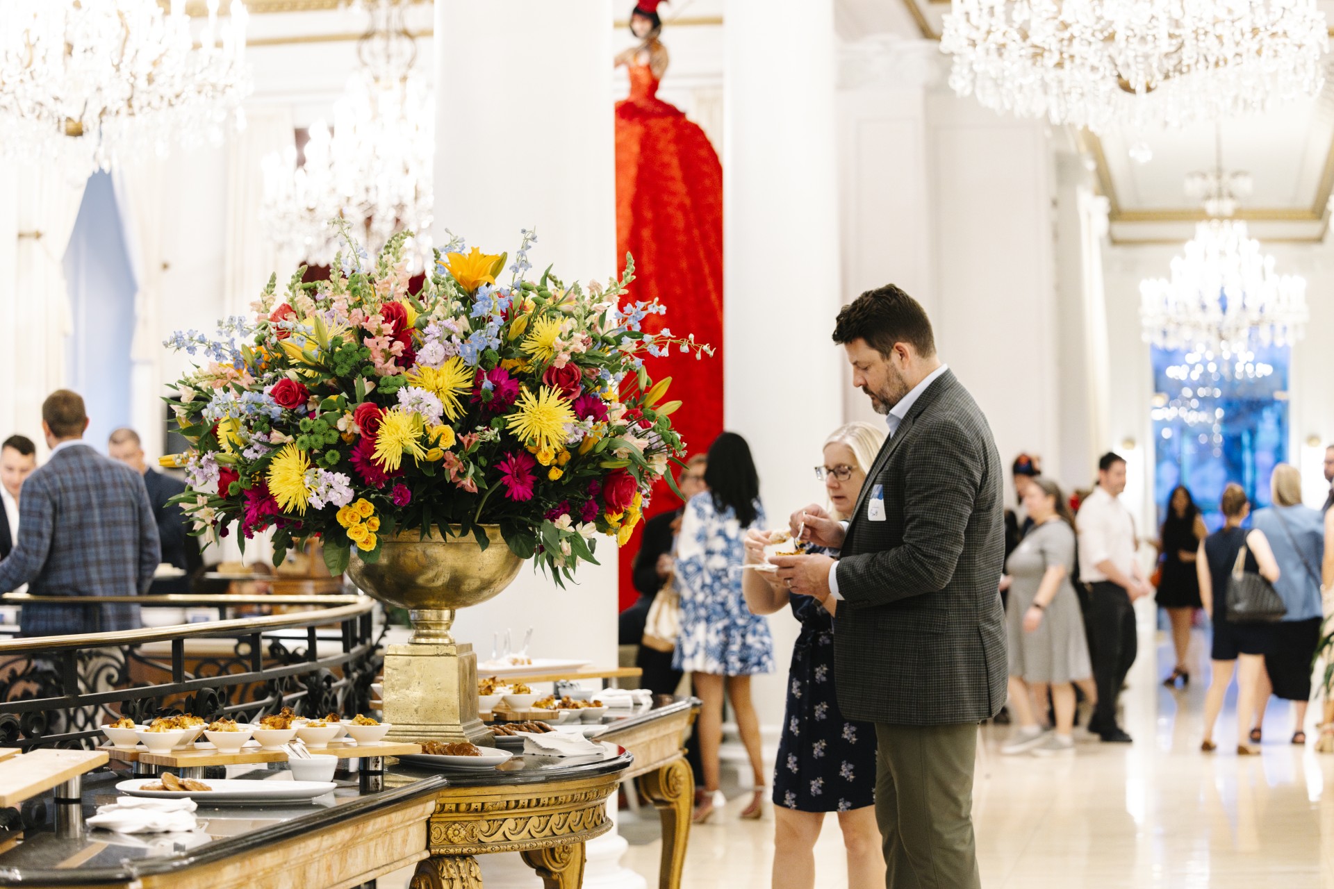 a man and woman standing next to a large vase of flowers