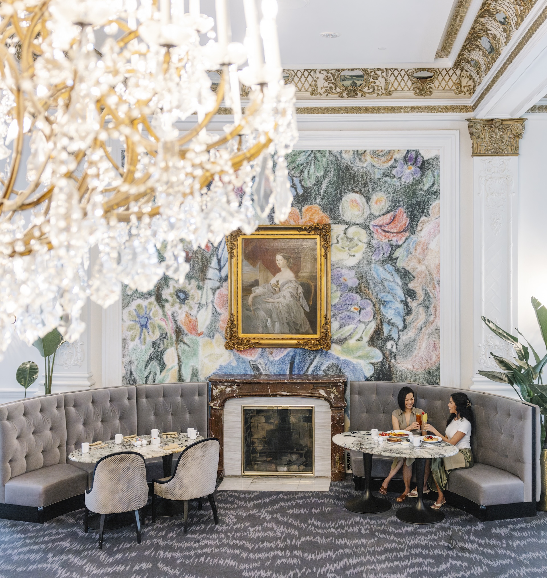 a group of women sitting at a table in a room with a fireplace