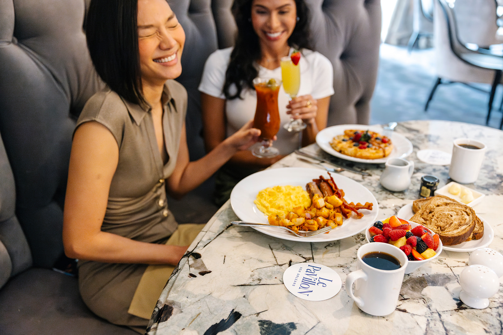 a couple of women sitting at a table with food and drinks