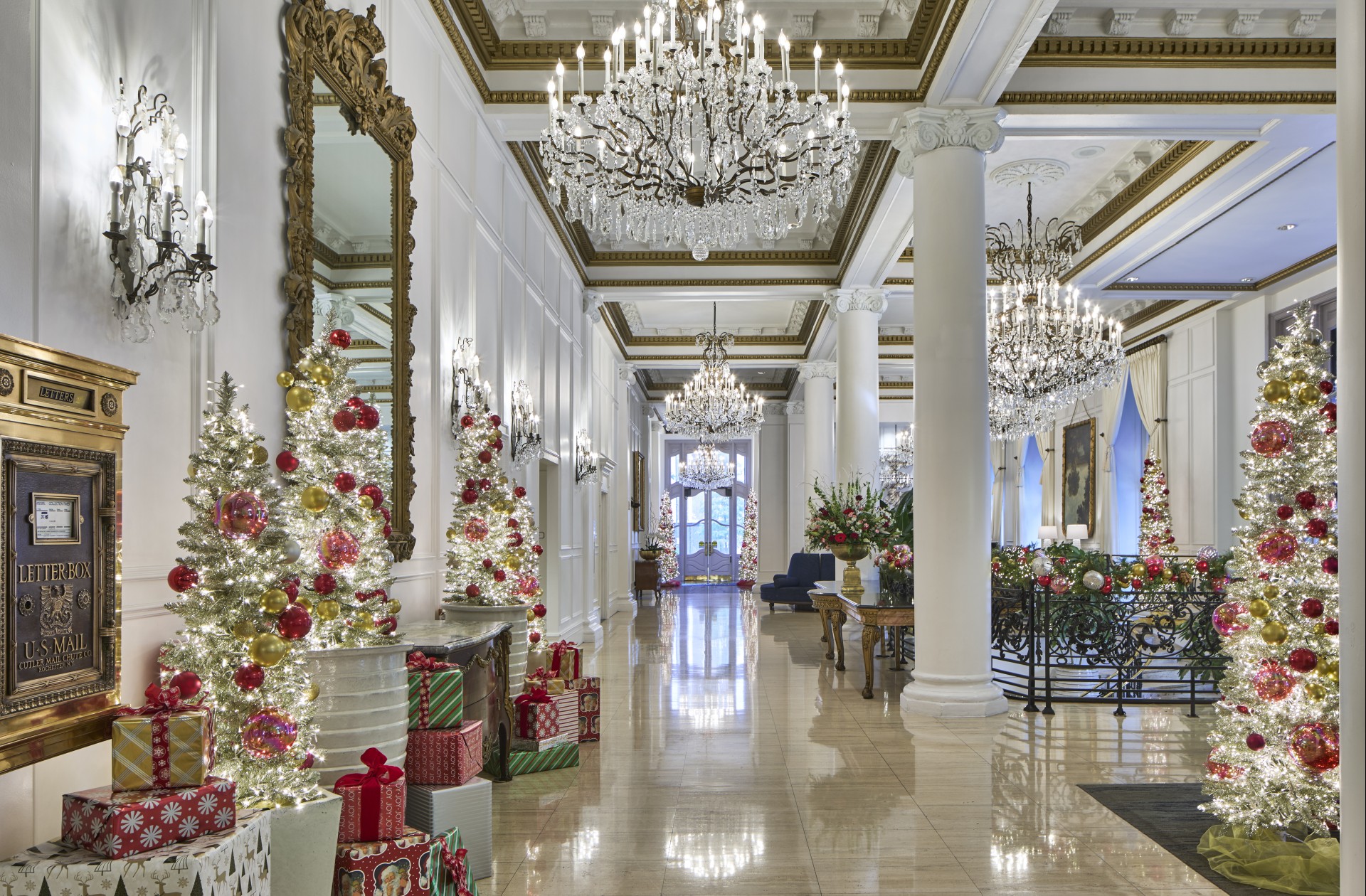 a large white hallway with a large chandelier and christmas tree